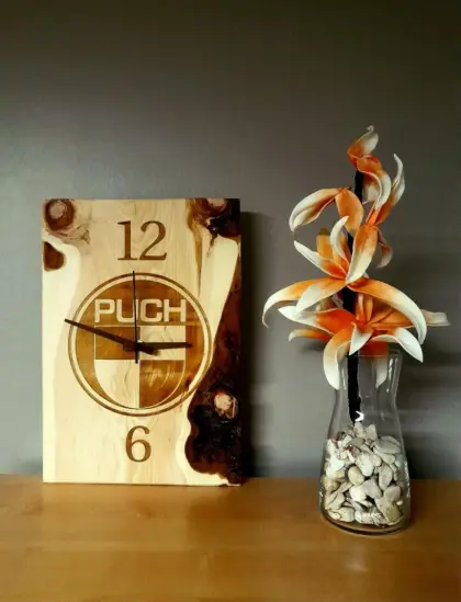 Puch-Wanduhr aus Zirbenholz mit Puch-Logo.